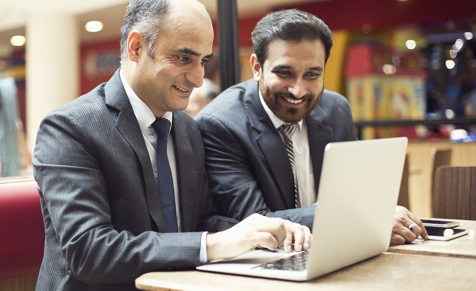 Two professionals of different age groups seated and looking at a laptop screen