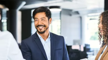 Businessman smiling and shaking hands in an office setting.