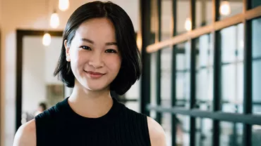 An East Asian woman smiling at the camera, in an office setting