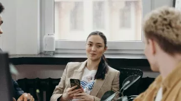 A group of three people having a meeting in an office setting.