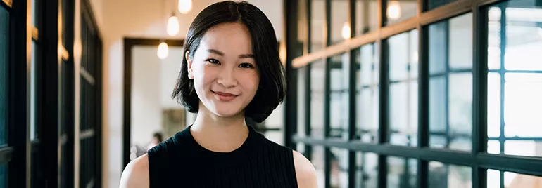 An East Asian woman smiling at the camera, in an office setting